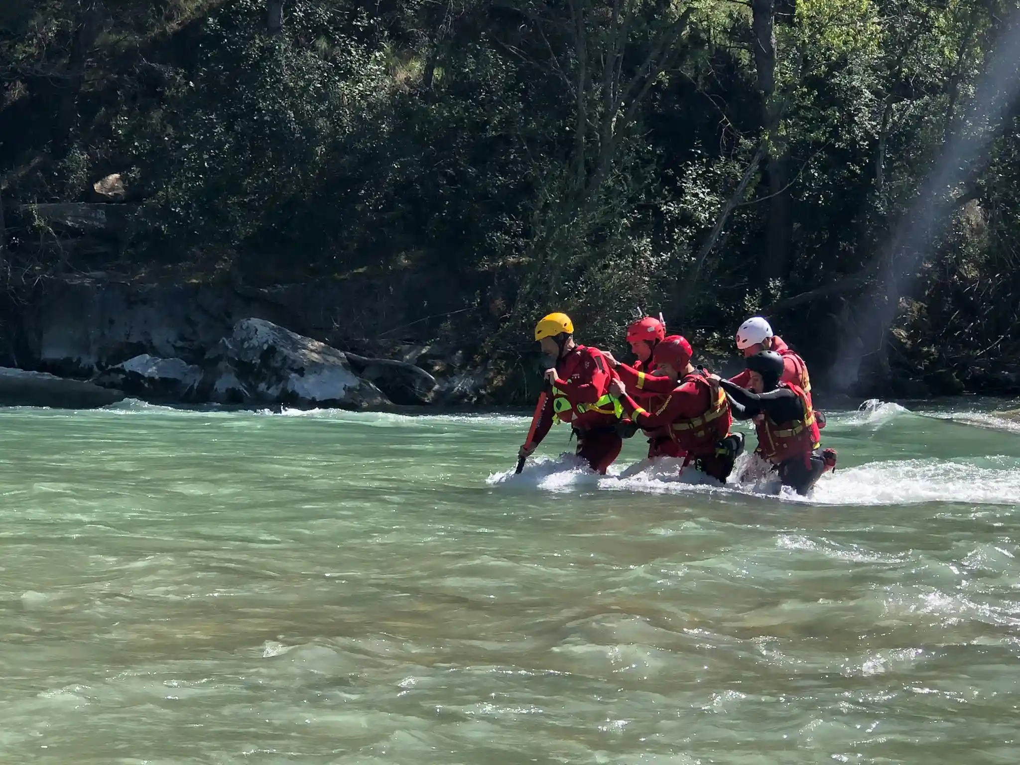 Grupo de rescateistas haciendo una práctica de vadeo en corriente durante un curso de rescate acuático
